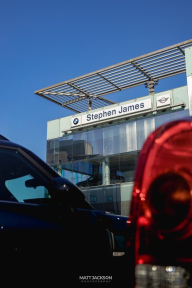 Building with "Stephen James" sign, blue sky, car visible in foreground.
