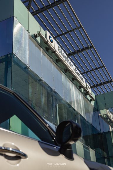 Modern building facade with glass panels and a car parked in front.
