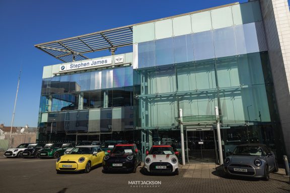 Exterior of a modern car dealership with various cars displayed in front.