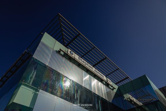 Modern glass building with a reflective facade under a clear blue sky.